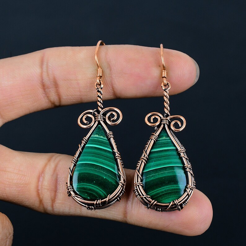 May include: A pair of copper wire wrapped earrings with green malachite teardrop shaped stones.