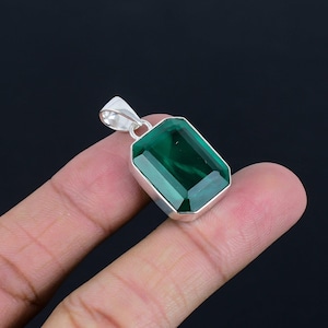 May include: A silver pendant featuring a large, emerald green gemstone cut in an emerald shape.