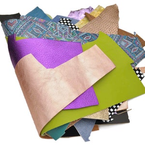 May include: A variety of leather scraps in different colors and patterns, including purple, green, gold, and blue. The scraps are arranged in a pile, with the edges of the leather overlapping.