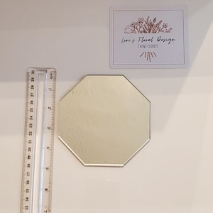 May include: A silver octagonal mirror with a textured surface. The mirror is approximately 3 inches in diameter.