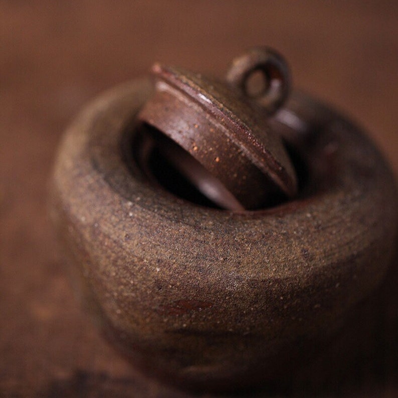 May include: A brown ceramic teapot with a lid. The teapot has a rough, textured surface and a small handle on the lid.