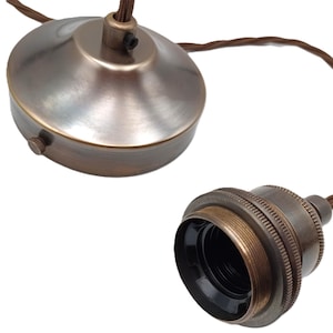 May include: A brass ceiling rose and a matching lamp holder with a black socket. The cord is brown and twisted.