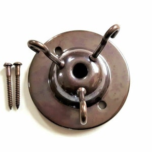May include: A bronze ceiling fixture with three hooks and two screws. The fixture is designed to hold light fixtures or other hanging objects.