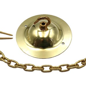 May include: A brass-coloured ceiling canopy kit, including a round canopy, chain, and screws. The canopy has a hook for hanging a light fixture. The chain is made of brass-coloured links.