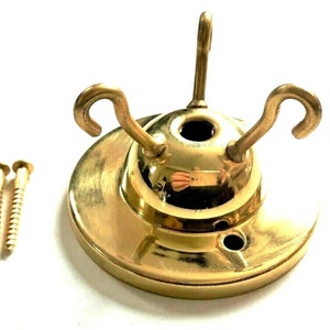 May include: A gold-toned metal ceiling fixture with three hooks and two screws. The fixture has a round base and a domed top.