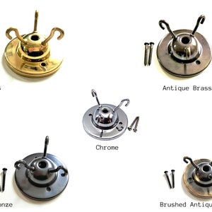 May include: Five different ceiling light fixture canopy plates in various finishes: brass, antique brass, chrome, dark bronze, and brushed antique. Each plate has three hooks and comes with two screws.