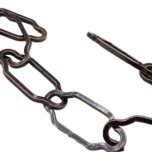 May include: Close-up of a decorative chain link in a bronze finish. The chain links have a unique, irregular shape, with a mix of rounded and angular forms. The metal has a slightly textured surface. The chain is set against a white background.