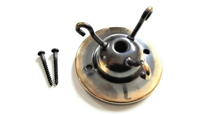 May include: A brass ceiling fixture with three hooks and two black screws. The fixture has a round base with a gold-colored rim.