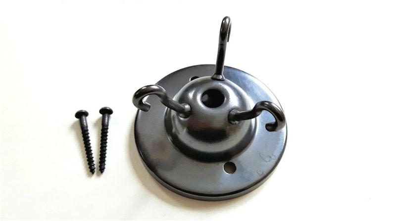 May include: Black metal ceiling fixture with three hooks and two screws. The fixture has a round base with a hole in the center.
