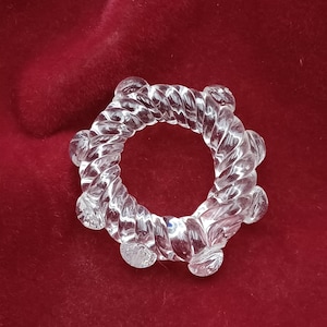 Puede incluir: Un anillo de vidrio transparente con un diseño de cuerda y bordes redondeados.