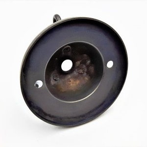 May include: A black metal ceiling fixture with a round, flat base and a central hole for a light bulb. The fixture has three small holes around the edge.