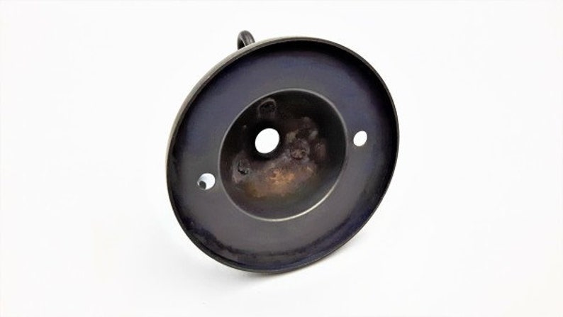 May include: A black metal ceiling fixture with a round, flat base and a central hole for a light bulb. The fixture has three small holes around the edge.