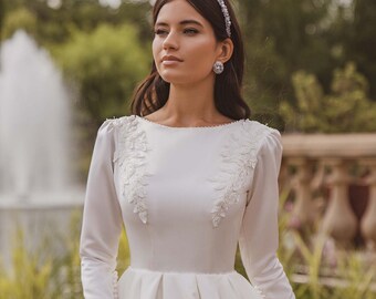 Satin wedding dress with long sleeves. The bodice dress is embroidered with beads and lace. The back of the dress with embroidery and beads