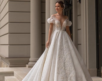 Robe de mariée luxueuse en tulle brillant à motifs et paillettes avec ornement en dentelle le long de la jupe et du corsage. Robe incroyablement belle