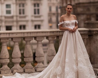 Robe de mariée élégante en dentelle. Une robe à fleurs et une traîne cathédrale. Robe de mariée brillante avec des fleurs volumineuses et des épaules ouvertes