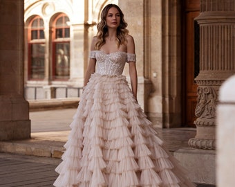 Une robe de mariée luxuriante avec des épaules ouvertes. Une robe avec une jupe en tulle en cascade luxuriante. Robe de mariée corset avec corsage lumineux