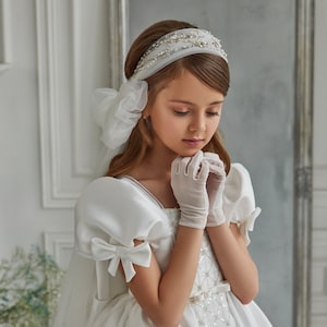 Satin communion dress. Ivory baby dress in royal satin embellished with geometric sequin embroidery on the bodice. Dress with a huge bow