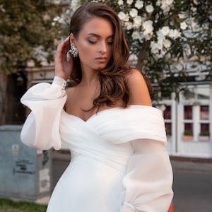 Feminine wedding dress in "Godde" style from stretch satin and chiffon. Off-the-shoulder dress with long, voluminous chiffon sleeves