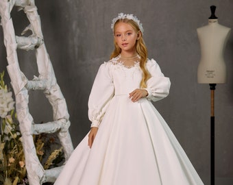 Satin white communion dress with long voluminous sleeves.  Dress for the first communion. White satin communion dress with lace