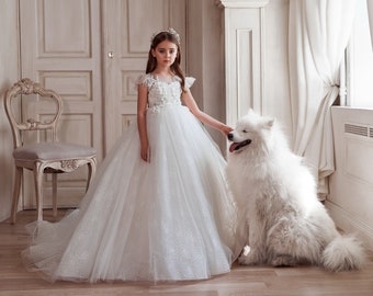 A radiant flower girl dress with floral details embroidered with beads on the bodice. The dress is completed with shining sleeves - wings