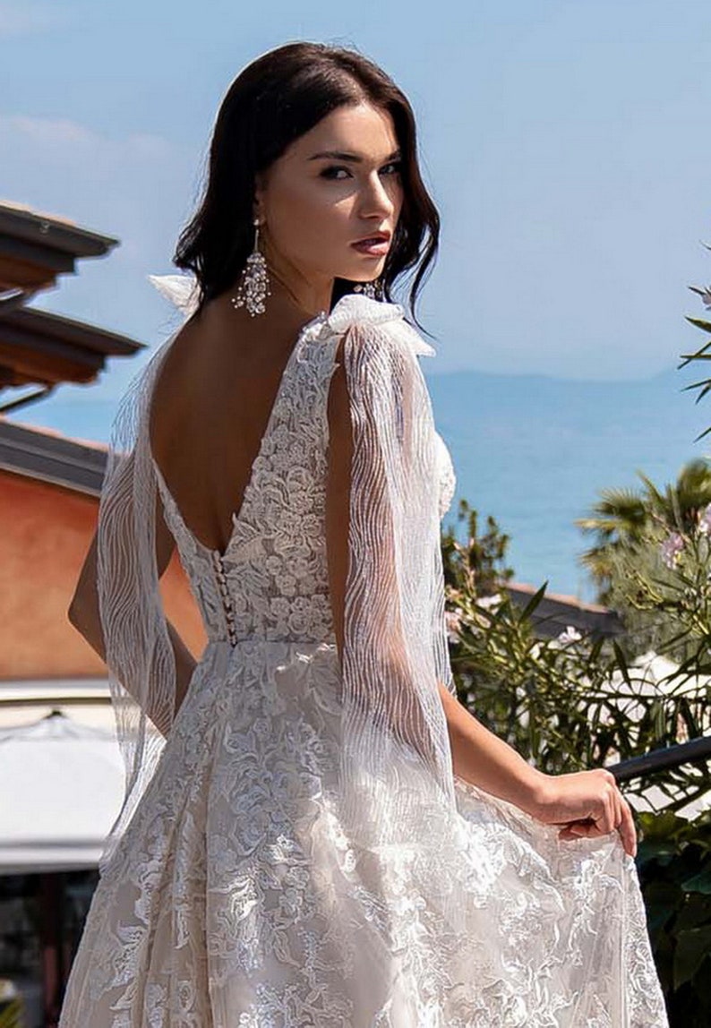 Gorgeous wedding dress made of expensive lace. The dress is decorated on the shoulders with removable tulle bows with glitter image 6