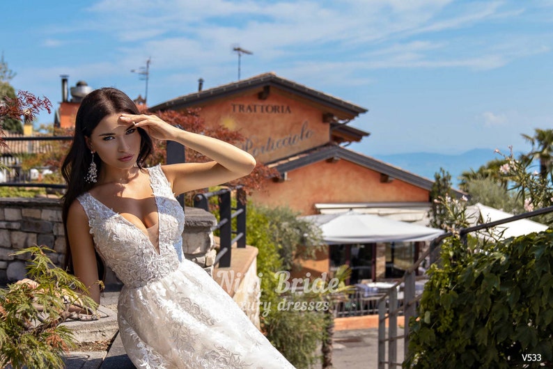 Gorgeous wedding dress made of expensive lace. The dress is decorated on the shoulders with removable tulle bows with glitter image 5