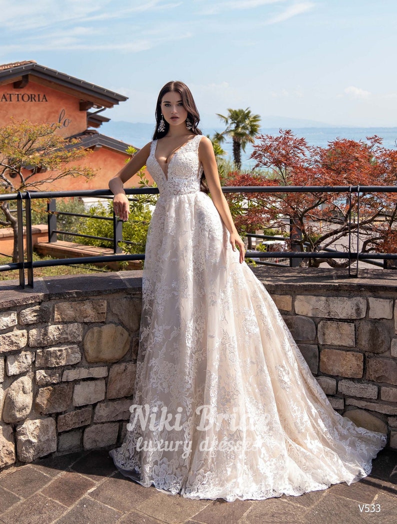 Gorgeous wedding dress made of expensive lace. The dress is decorated on the shoulders with removable tulle bows with glitter image 1