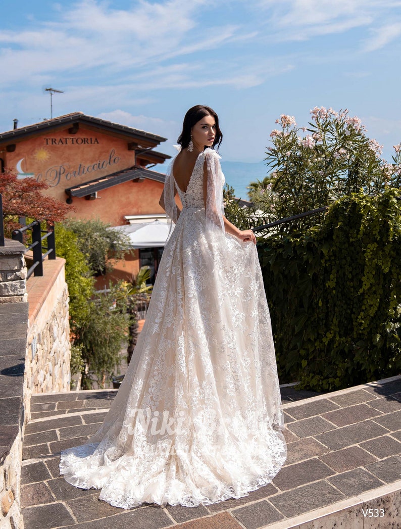 Gorgeous wedding dress made of expensive lace. The dress is decorated on the shoulders with removable tulle bows with glitter image 3