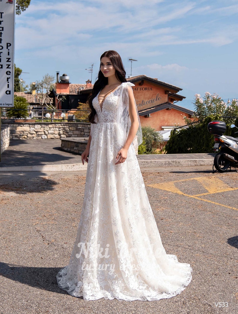 Gorgeous wedding dress made of expensive lace. The dress is decorated on the shoulders with removable tulle bows with glitter image 2