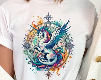May include: White t-shirt featuring a colorful illustration of a winged unicorn inside a circular design with symbols. The unicorn has a blue mane and tail, with a rainbow-colored body and wings. The design is surrounded by a border of symbols and colors.
