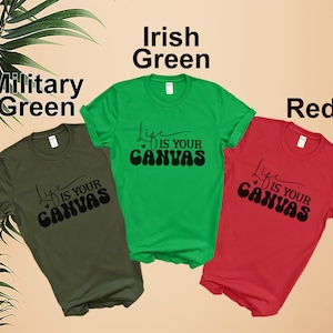 Pode incluir: Tr&ecirc;s camisetas em cores diferentes: verde militar, verde irland&ecirc;s e vermelho. Cada camiseta apresenta um gr&aacute;fico preto que diz "Life is your canvas".