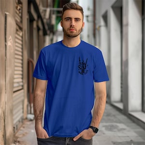 Pode incluir: Uma camiseta azul royal com um gr&aacute;fico preto de uma m&atilde;o fazendo o sinal de rock and roll. O gr&aacute;fico tamb&eacute;m inclui as palavras "Rock Life" em uma fonte estilizada.