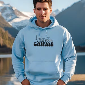 Pode incluir: Um moletom azul claro com um gr&aacute;fico preto que diz "Life is your canvas".
