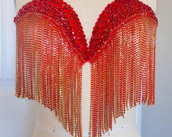 May include: A red and gold beaded fringe top. The top is strapless and has a sweetheart neckline. The fringe is made of small beads that are strung together in long strands.