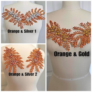 K&ouml;nnte beinhalten: Drei Strass-Applikationen in Orange und Silber oder Gold werden auf Schneiderpuppen gezeigt. Die Applikationen weisen Blumen- und Blattmuster auf. Der Text darunter lautet "Orange & Silver 1", "Orange & Gold" und "Orange & Silver 2".