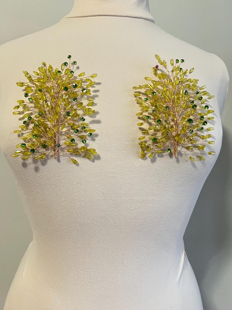 May include: Two decorative floral appliques. Each applique features a branch-like design crafted with yellow and green beads. The beads are attached to a thin, gold-colored wire frame. The appliques are displayed on a white mannequin.