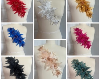 May include: A collection of decorative floral appliques in various colors, including red, white, gold, blue, pink, black, peach, and teal. Each applique features a layered design with feathers and bead accents, displayed on a mannequin.