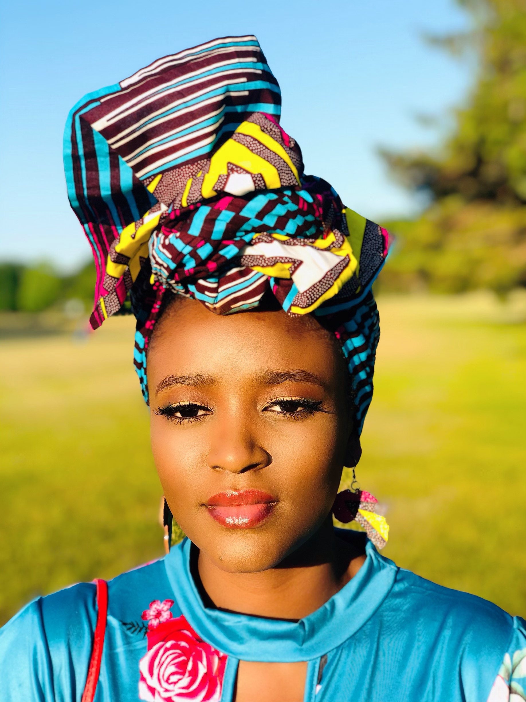 African print head wrap and large disc earrings in a multi colour geometric print with black.