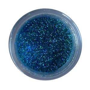 May include: A small jar filled with teal blue glitter. The glitter has a slight iridescent sheen.