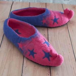 May include: A pair of pink and blue wool slippers with a pointed toe and star designs. The slippers are made of felted wool and have a soft, comfortable feel.