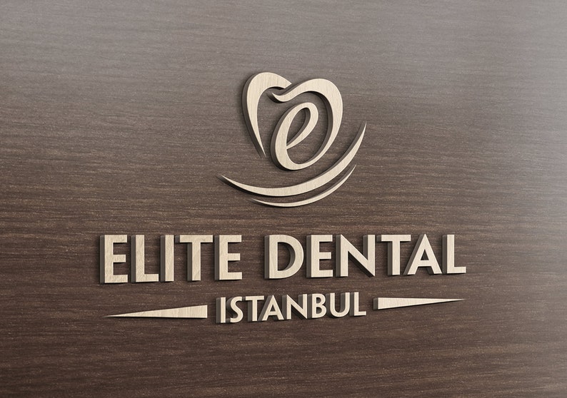 May include: A three-dimensional logo sign featuring the text ELITE DENTAL ISTANBUL in a light beige, metallic finish. Above the text is a stylized icon resembling a tooth with a lowercase letter e inside, all set against a dark wood grain background.