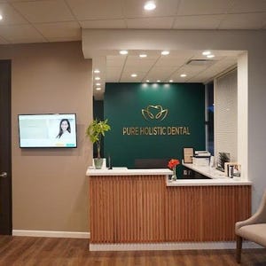 Here, the green wall in the reception lobby of a dental clinic features a custom logo consisting of the client's logo and the name of the clinic in brushed gold metal lettering.
