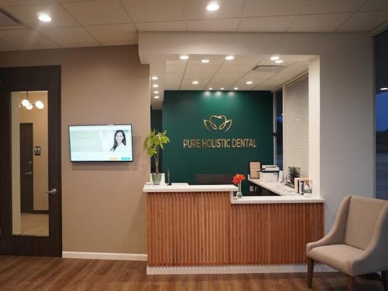 Here, the green wall in the reception lobby of a dental clinic features a custom logo consisting of the client's logo and the name of the clinic in brushed gold metal lettering.
