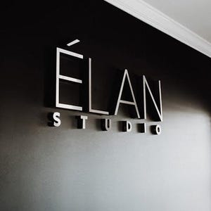 This photo shows the sign “ELAN STUDIO” on a dark wall, a business sign personalized specifically for the client.