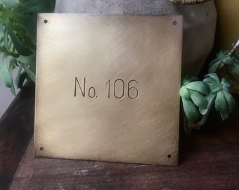 May include: A brass plaque with rounded corners and four holes. The plaque has the text "No. 106" engraved on it.