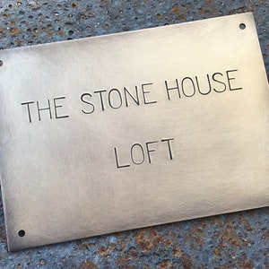 May include: A brass plaque with the text "THE STONE HOUSE LOFT" engraved on it. The plaque has four holes around the edges.