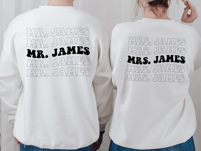 K&ouml;nnte beinhalten: Zwei wei&szlig;e Sweatshirts mit schwarzem Text. Der Text auf dem linken Sweatshirt lautet "MR. JAMES" f&uuml;nfmal. Der Text auf dem rechten Sweatshirt lautet "MRS. JAMES" f&uuml;nfmal.