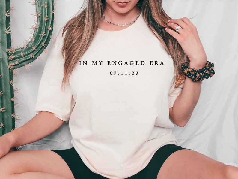 May include: A white t-shirt with the text "IN MY ENGAGED ERA 07.11.23" printed on the front.
