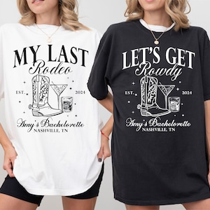 May include: Two white t-shirts with black text and graphics. The text on the left shirt reads "My Last Rodeo" and the text on the right shirt reads "Let's Get Rowdy". Both shirts feature a boot and a cocktail glass graphic. The text "Amy's Bachelorette Nashville, TN" appears below the graphics on both shirts.