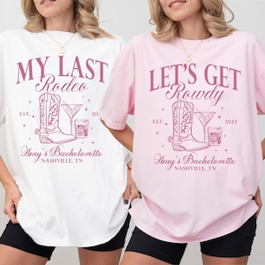 May include: Two white t-shirts with pink text and graphics. The left shirt says "My Last Rodeo" with a boot and a cocktail glass. The right shirt says "Let's Get Rowdy" with a boot and a cocktail glass. Both shirts say "Amy's Bachelorette Nashville, TN".